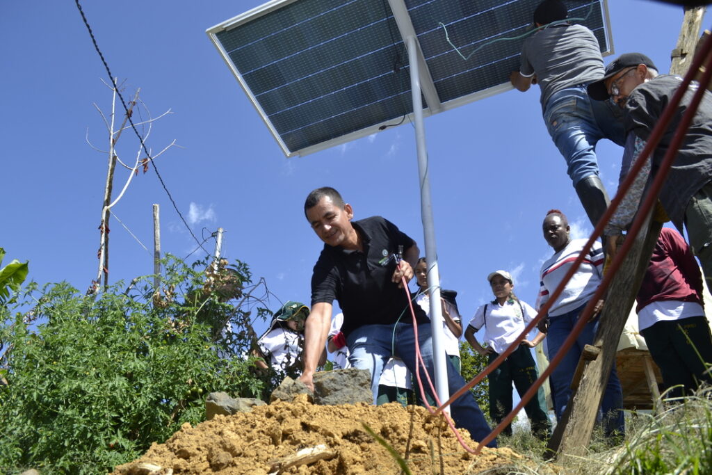 Ebiliardo Martínez, técnico de la Escuela de Formación de Técnicos Comunitarios en Energías Alternativas, ayuda a instalar el panel solar en casa de Acened Higuita.