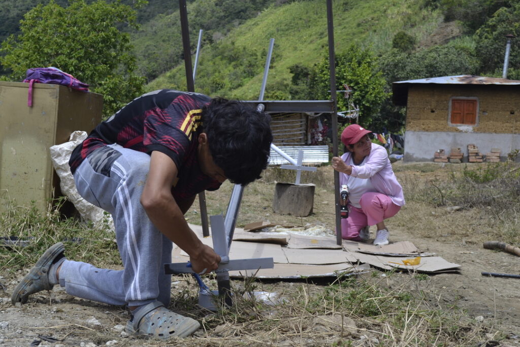 Franquelina David y su hijo trabajan en la estructura que sostendrá el panel solar de su hogar.