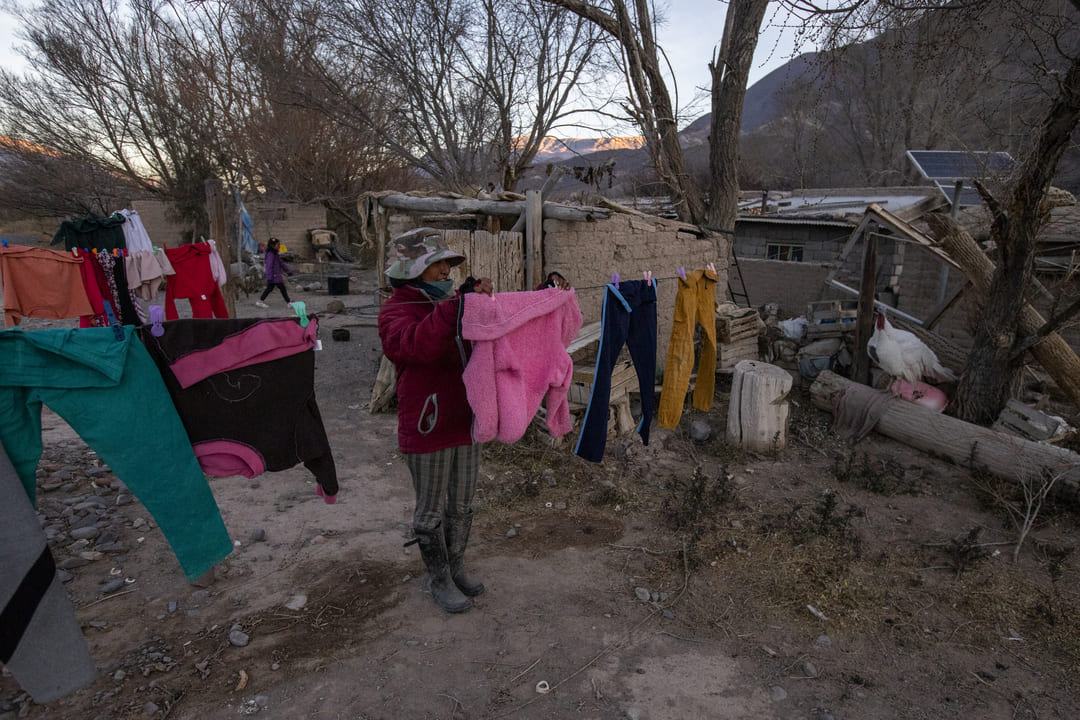 Rosita termina de colgar la ropa al atardecer frente a su casa en Gobernador Solá, Salta, Argentina. Los cerros recortan el cielo con los colores cálidos del ocaso. La vida sigue, al fin y al cabo.