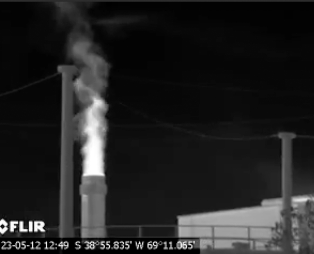 YPF Refinería Plaza Huincul, 12 de mayo de 2023
La foto digital de la chimenea detrás de un tanque dentro de la Refinería Plaza Huincul YPF no demuestra señales visibles de emisiones de gases o bruma de calor, en cuanto la captura de pantalla del video de OGI filmado al mismo tiempo registra lo que aparentan ser plumas de contaminación de hidrocarburos que incluyen metano y otros compuestos nocivos que resultan del proceso de combustión incompleta. Foto: Earthworks